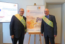 Prof. Dr. Wolfgang Schareck und Oberbürgermeister Roland Methling präsentieren das Plakat zur Staffelstabübergabe