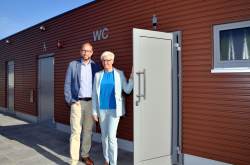 Steffi Berger, Geschäftsführerin der Fima Berger Raumsysteme GmbH, und Tourismusdirektor Matthias Fromm präsentieren in Warnemünde die neue Toilette am Strandaufgang 10.