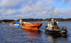 Die "MS Undine" wird vom Rostocker Stadthafen in den Fischereihafen verbracht und dort an Land gehoben.