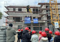 Hortkinder  mit kleinen roten Bauhelmen beim Richtfest vor dem Hortrohbau