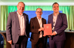 Übergabe des Fördermittelbescheids durch Dr. Wolfgang Blank (Mitte) an Dirk Inger (links) und Felix Petersen (rechts), Vorstand des MV Cruise Net e.V.