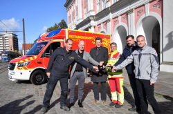 Senator Dr. Chris von Wrycz Rekowski übergibt auf dem Neuen Markt drei neue Rettungswagen an die künftigen Nutzer*innen.