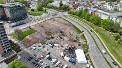 Luftaufnahme der Theaterbaustelle am Tag des Spatenstichs (29. April 2024). Auf der ehemaligen Parkplatzfläche an der Fischerbastion hat am 13. Mai 2024 die Erschließung des Regen- und Schmutzwasserstrangs begonnen. Er befindet sich am unteren Bildrand unterhalb der beiden kleinen weißen Zelte. 