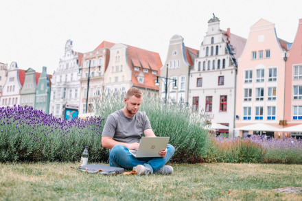 Student sitzt mit Laptop auf einer Wiese