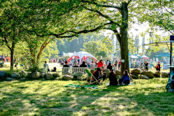 Besuchergruppe auf Decken und Klappstühlen beim Picknick im Stadtgrün