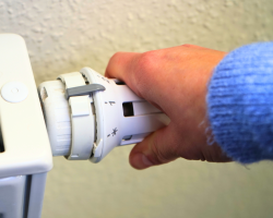 Hand dreht am Heizungsthermostaten Hand dreht am Heizungsthermostaten