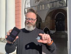 Oberbürgermeister Claus Ruhe Madsen mit der luca-App und dem luca-Schlüsselanhänger vor dem Rathaus