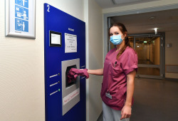 Gesundheitspflegefachfrau Anne Baum am Wäsche-Rückgabeschacht; ihre Karte wird umgehend wieder aufgeladen.