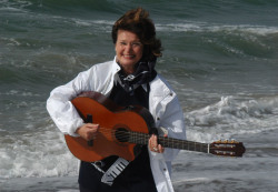 Musikerin Heide Mundo mit Gitarre am Strand von Warnemünde