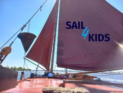 Blick über das Deck eines Traditionsseglers mit Sail4kids-Logo auf dem Großsegel