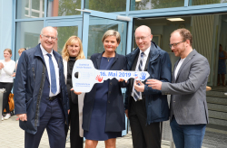 Oberbürgermeister Roland Methling, KOE-Chefin Sigrid Hecht, Infrastrukturminister Christian Pegel und Sozialsenator Steffen Bockhahn (v.l.n.r.) überreichen den symbolischen Schlüssel für die GodeWindSchule an die Schulleiterin Regina Moscha.